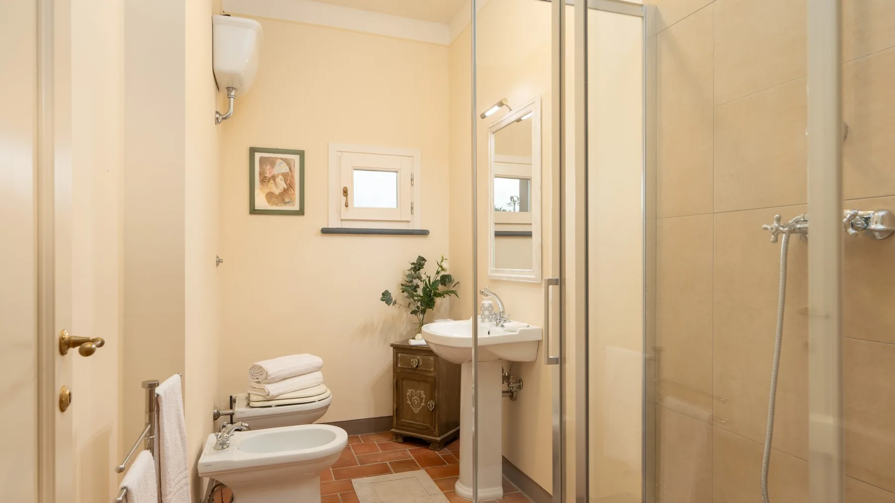 Un baño con lavabo, inodoro y ducha con mampara de vidrio.