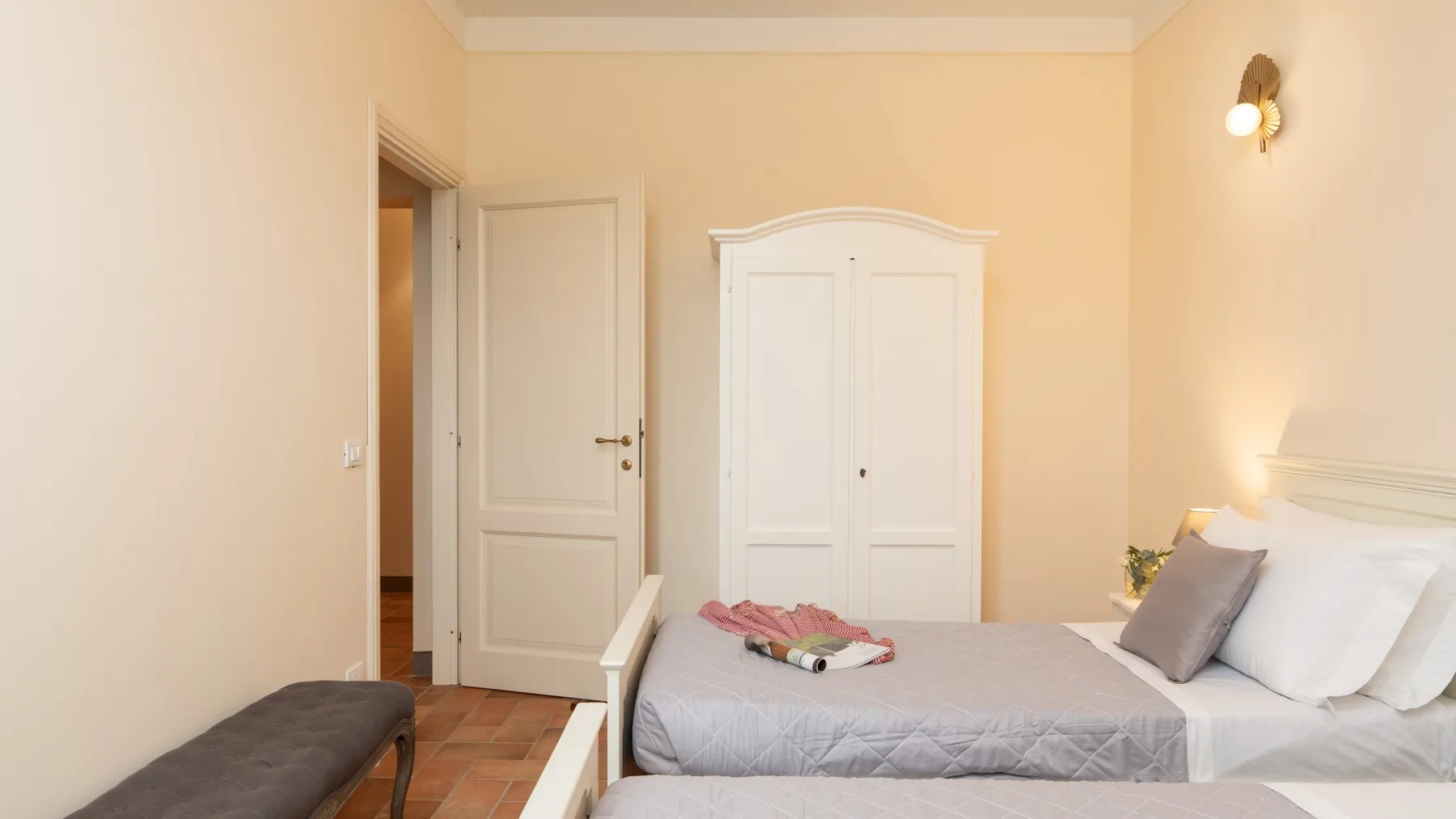Un dormitorio con una cama, un armario blanco y una puerta abierta.