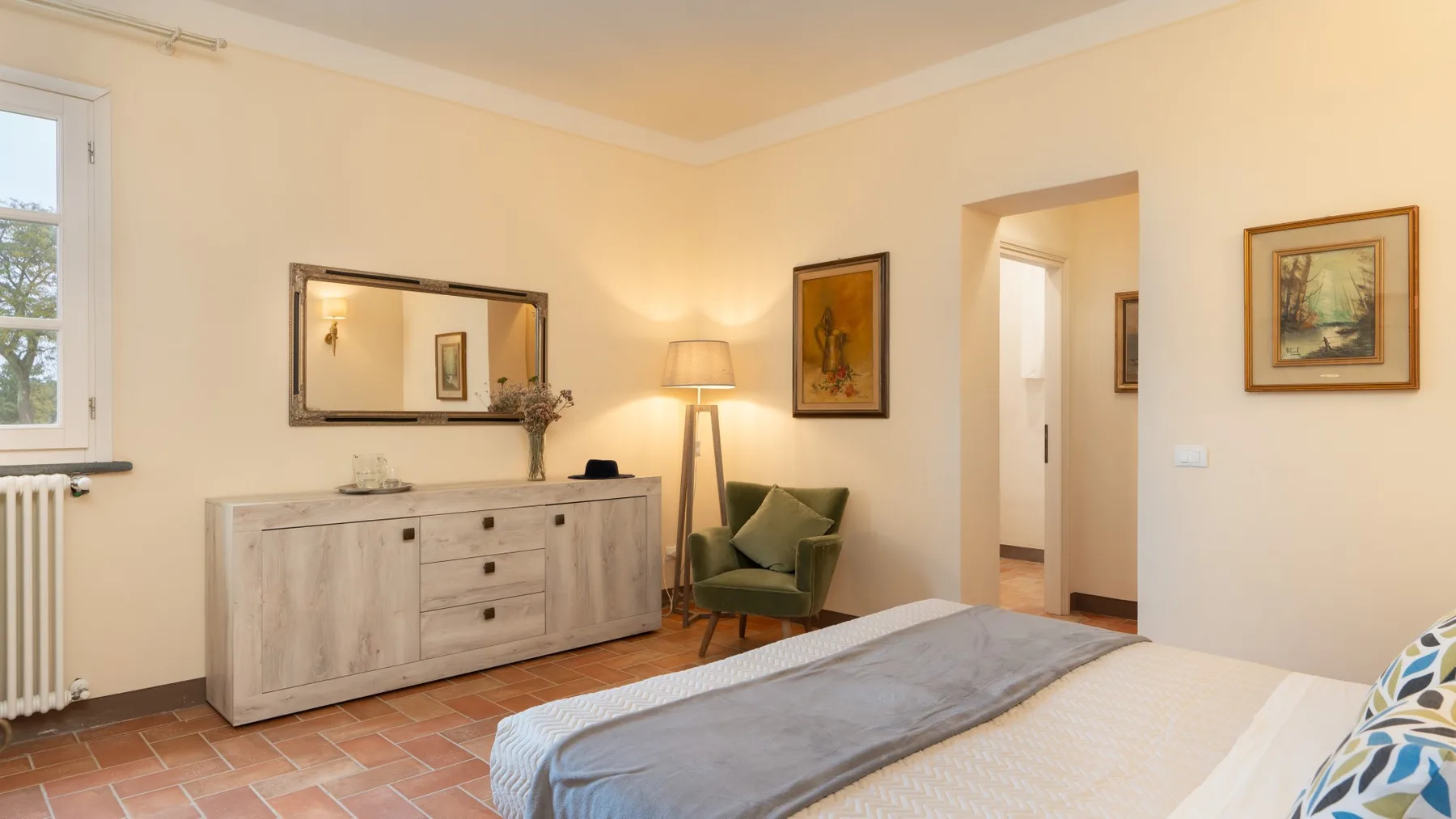 Un dormitorio con una cama, una cómoda y un sillón verde.