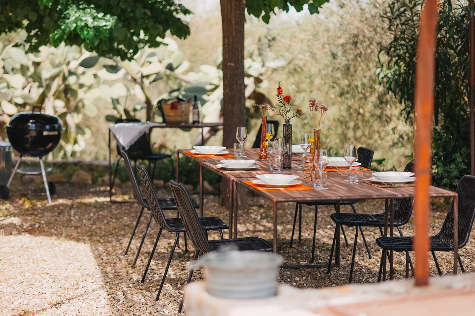 Una zona de comedor al aire libre con una mesa larga bajo árboles frondosos.