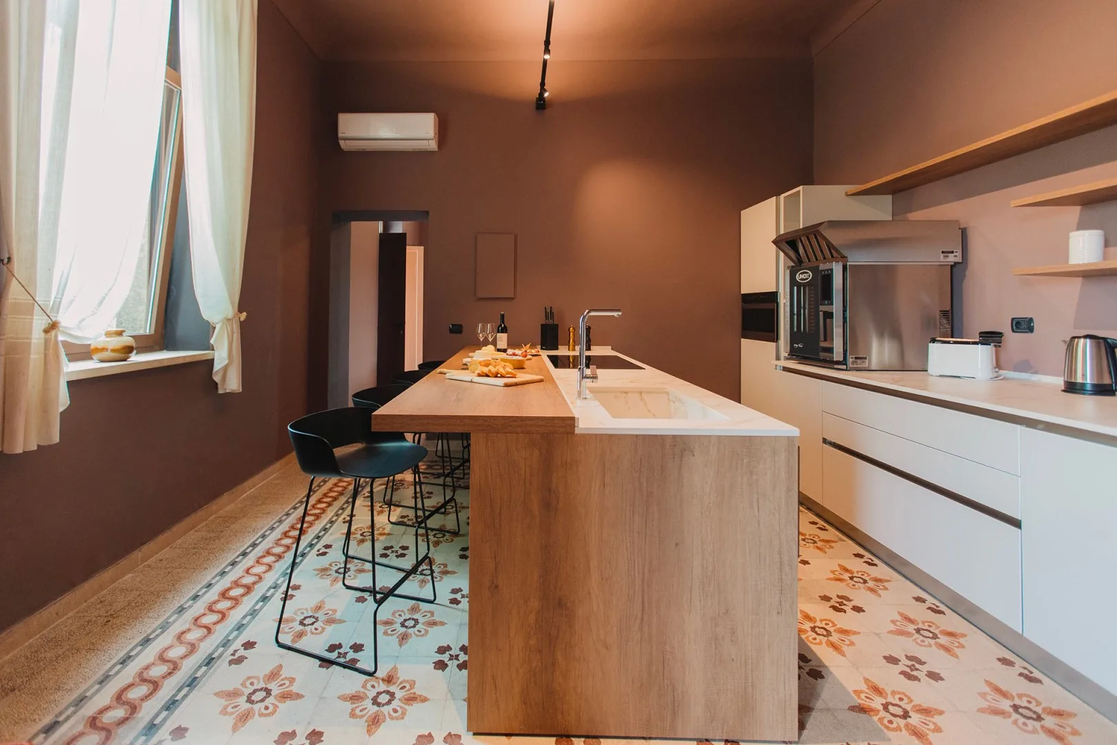 Una cocina moderna con una isla central y suelo de baldosas estampadas.