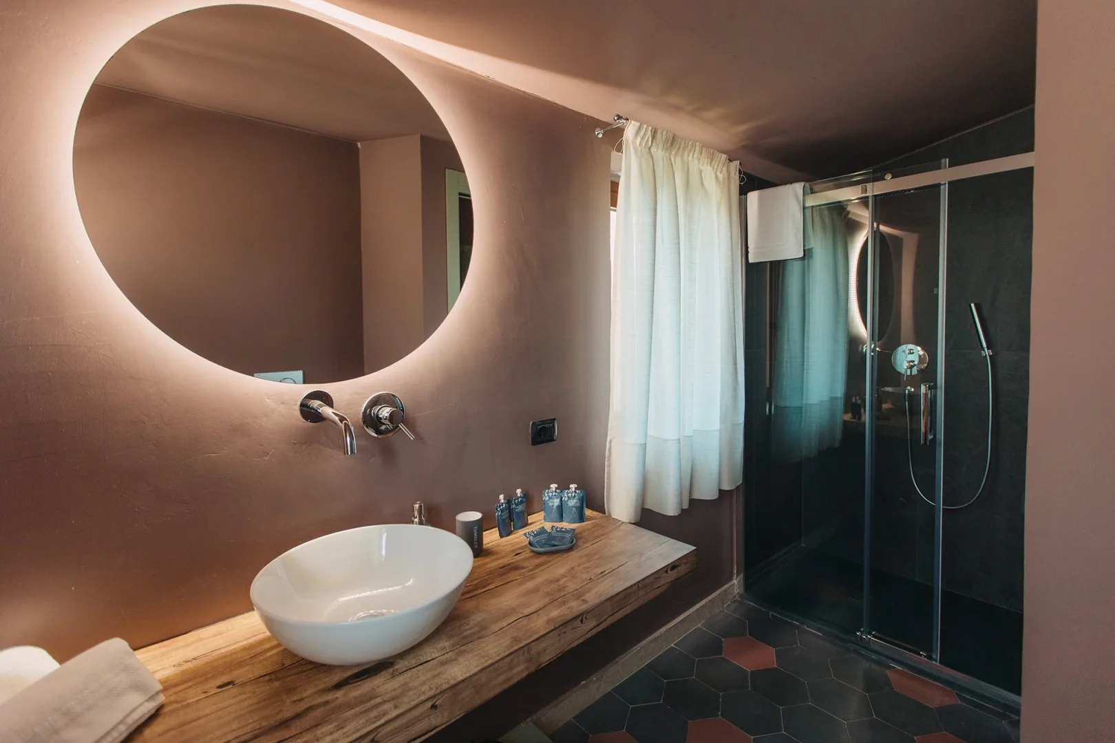 Un tocador de baño con lavabo sobre encimera y una ducha de vidrio al lado.