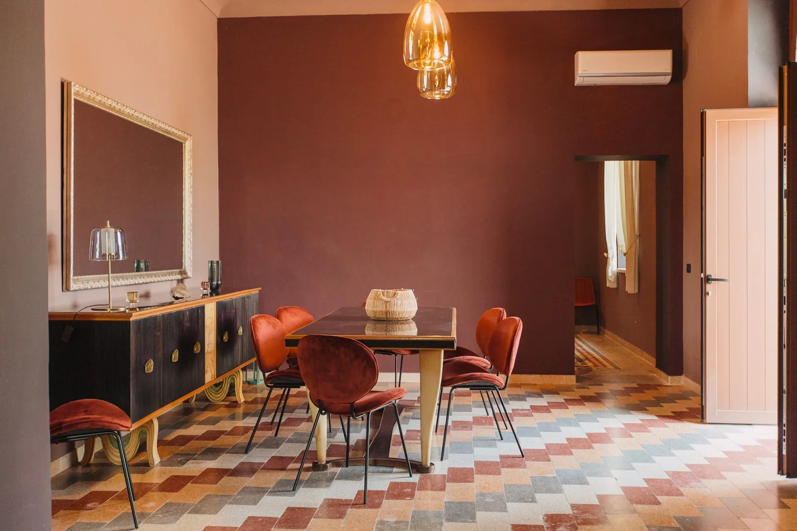 Comedor con una mesa y sillas frente a una pared oscura.