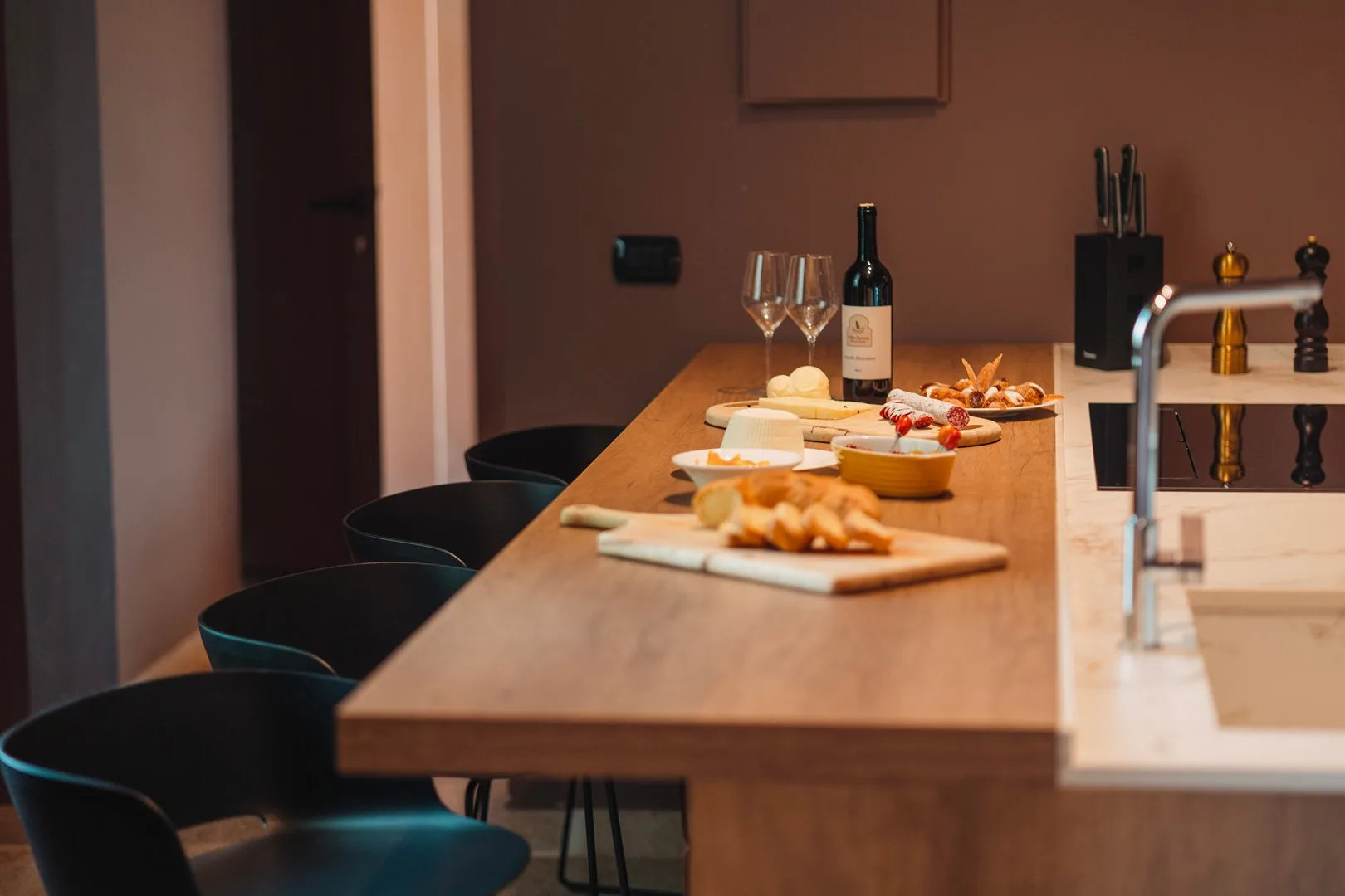 Una isla de cocina está preparada con platos de comida y una botella de vino.
