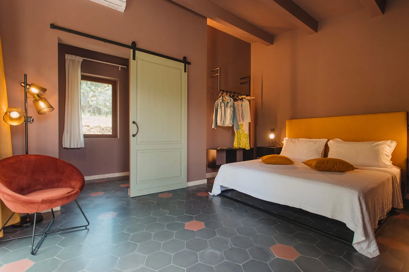 Un dormitorio con una cama grande, una puerta corredera y un sillón tapizado rojo.