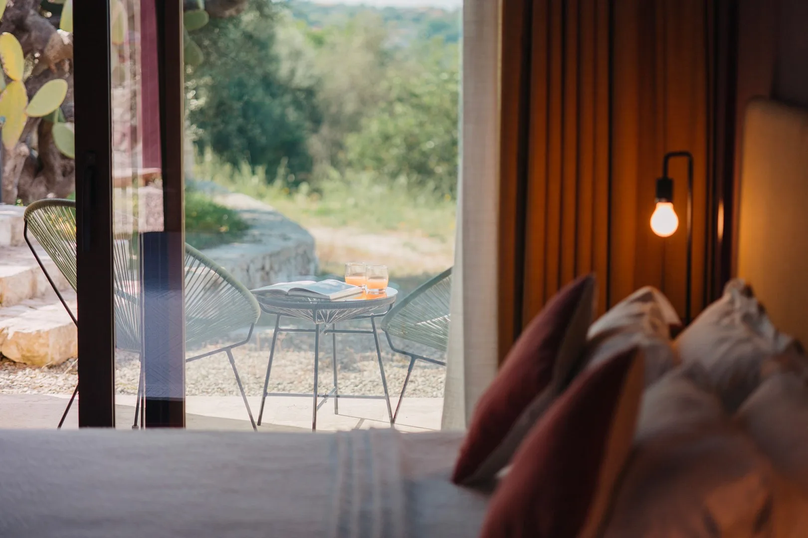 Una zona de estar junto a una ventana amplia da a sillas y una mesa en el exterior.
