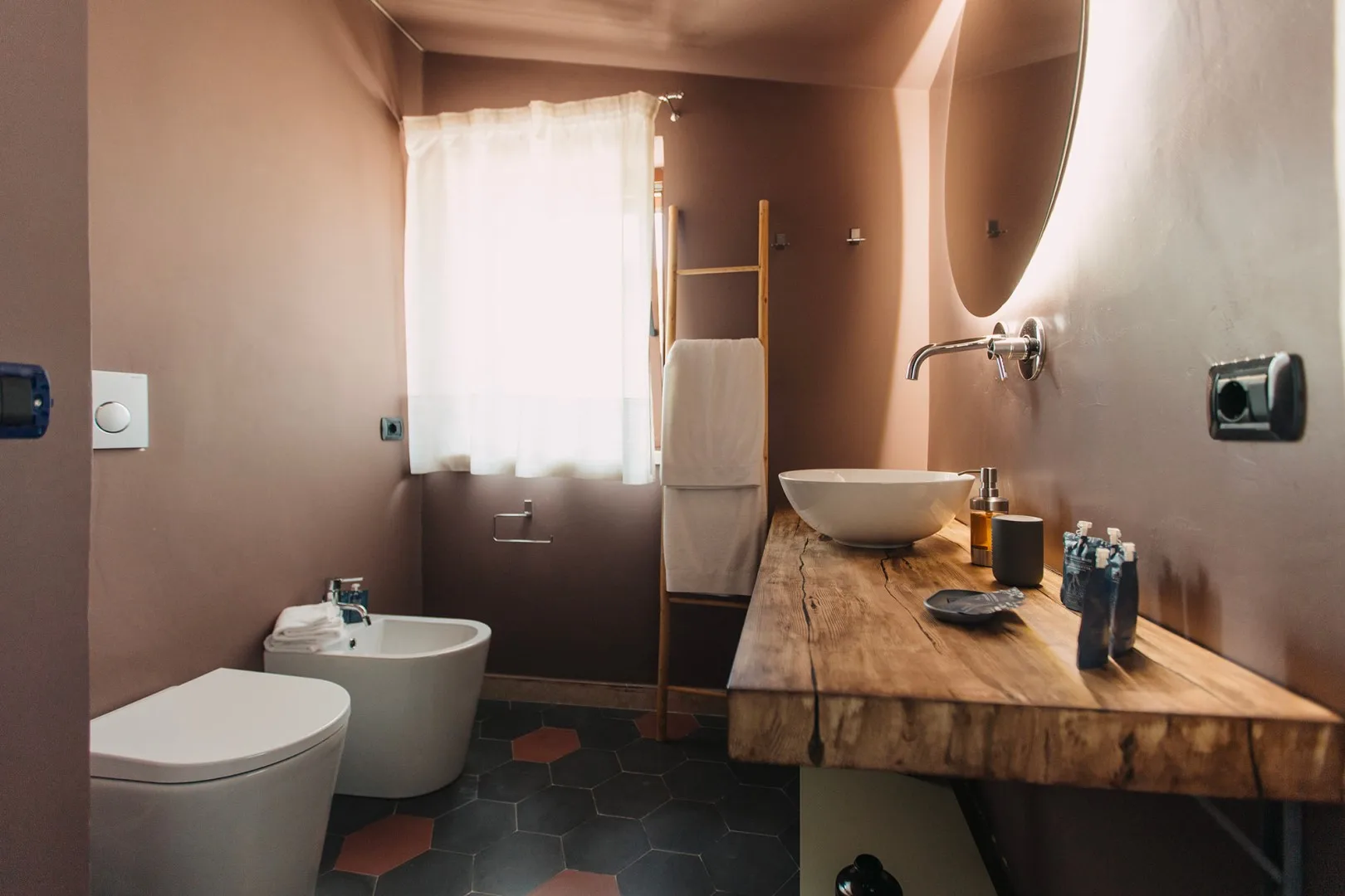 Un baño con inodoro, lavabo y encimera de madera bajo una ventana.