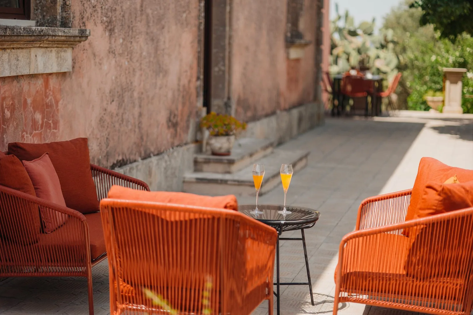 Asientos en un patio al aire libre con sillas naranjas y una mesa pequeña.