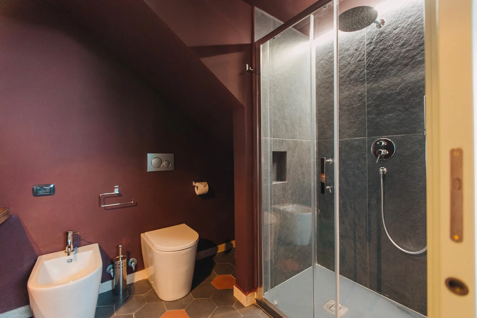 Un baño con lavabo e inodoro junto a una ducha con mampara de vidrio.