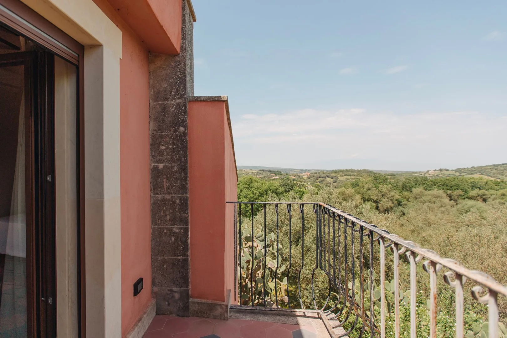 Un balcón ofrece vistas de un amplio paisaje verde bajo un cielo despejado.