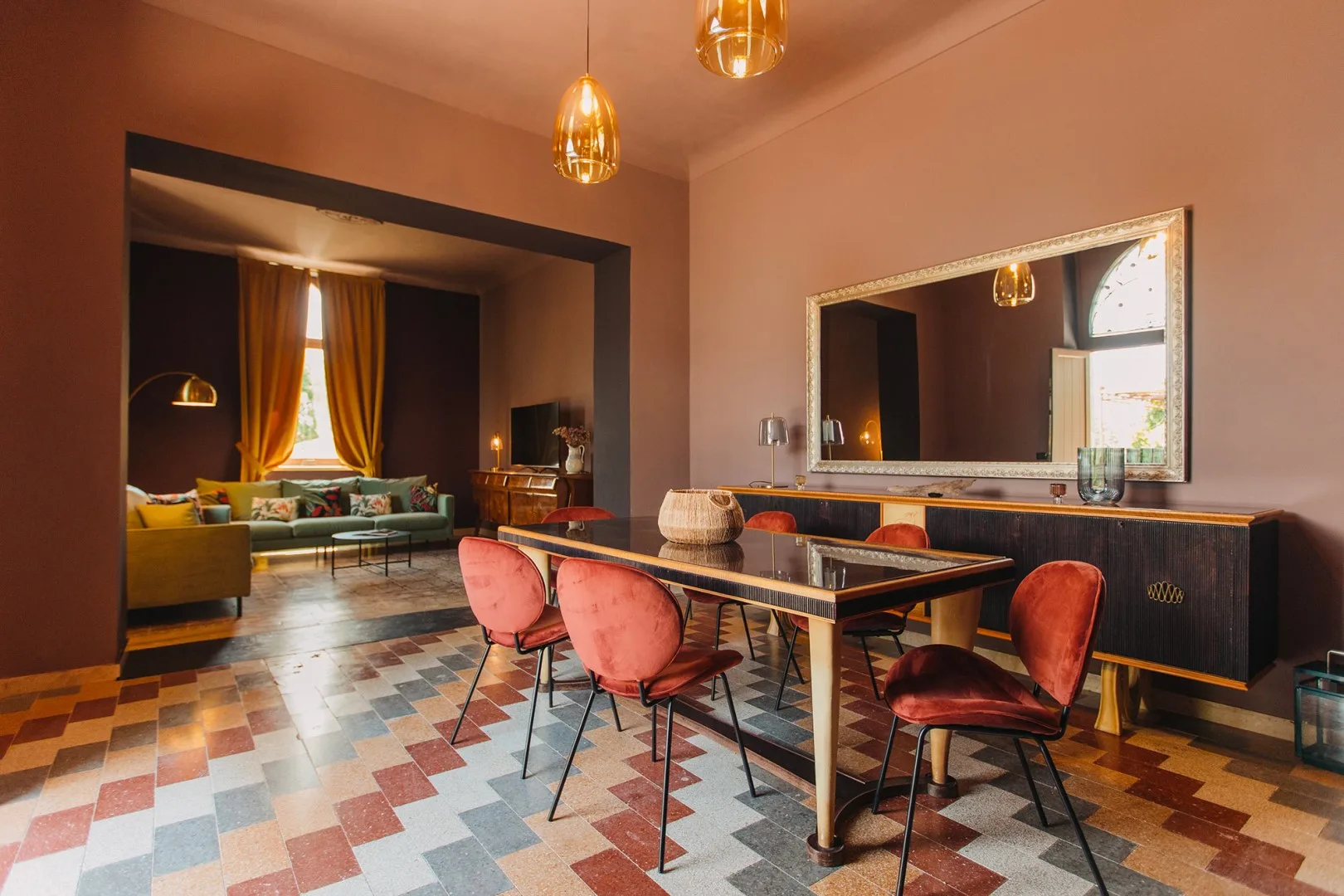 Comedor con una mesa larga y asientos tapizados junto a una sala de estar.