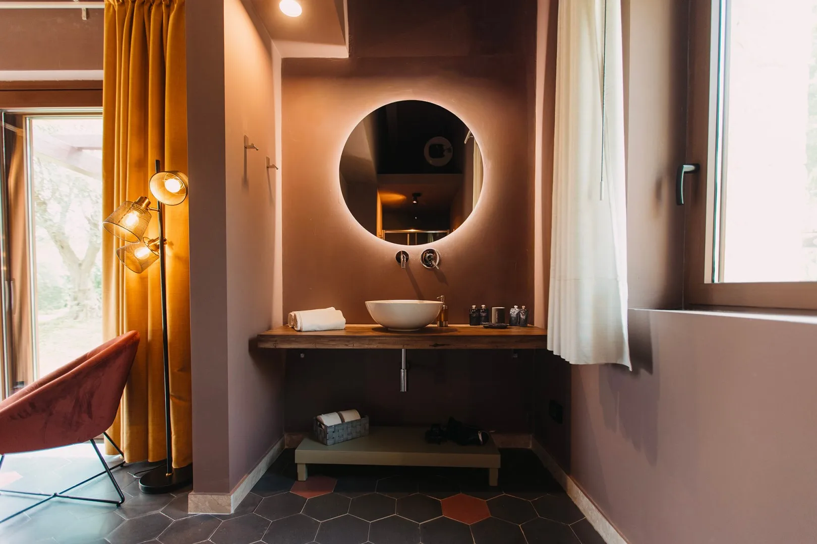 Un lavabo de baño con espejo redondo y lavamanos sobrepuesto.