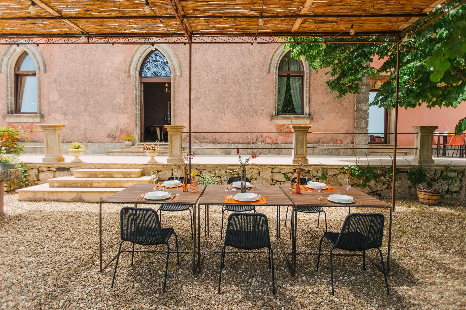 Una zona de comedor al aire libre está bajo un toldo junto a un edificio.