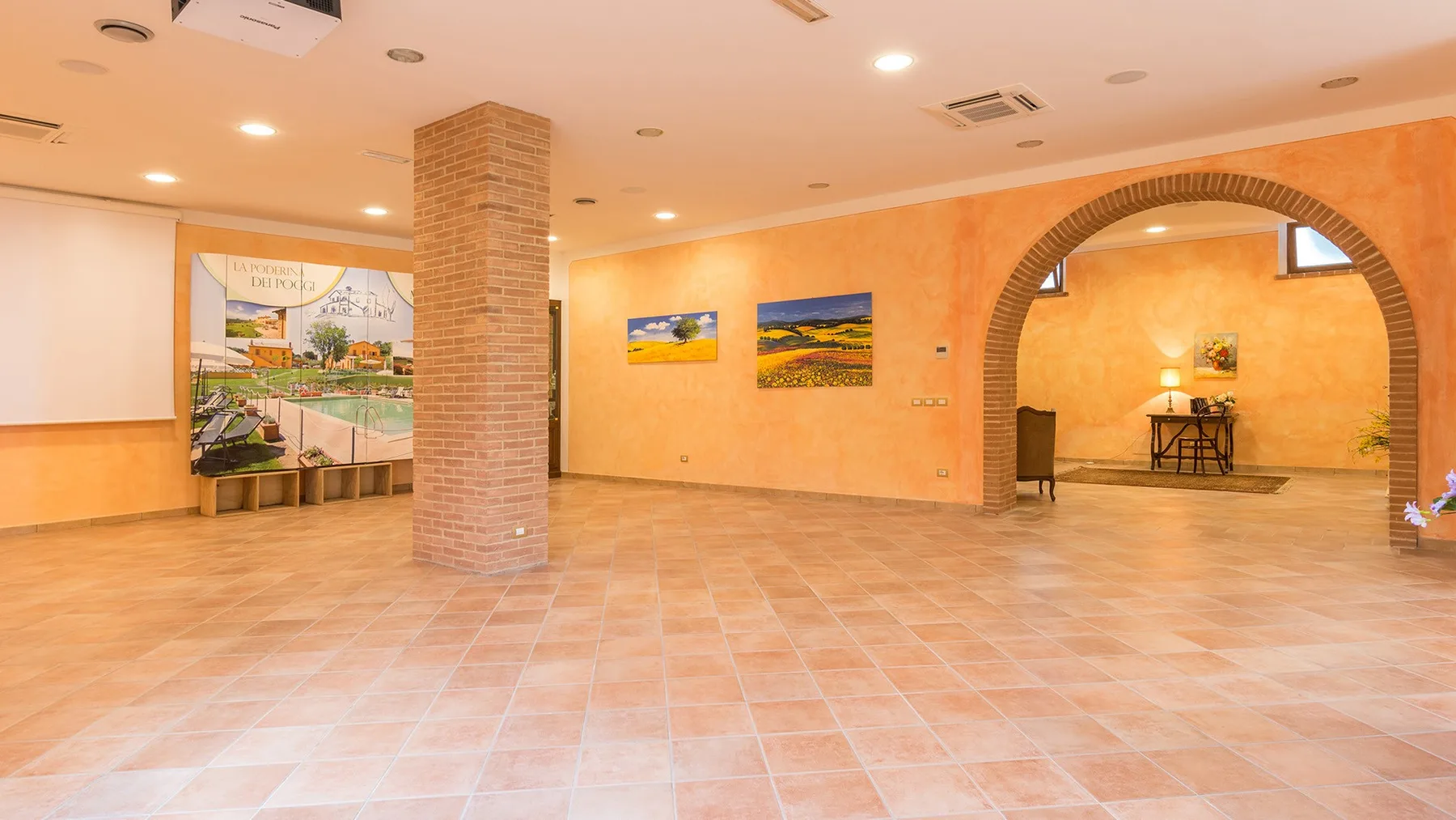 A spacious tiled interior hall with warm orange walls and an arched opening.