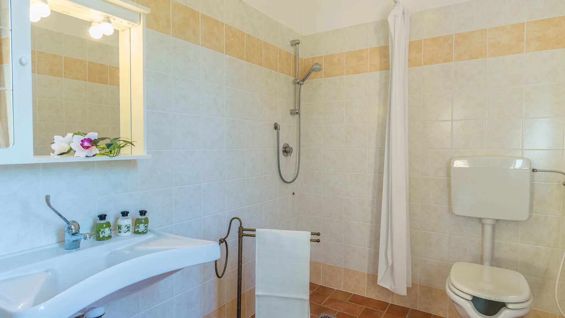 A tiled bathroom with a sink, shower, and toilet.