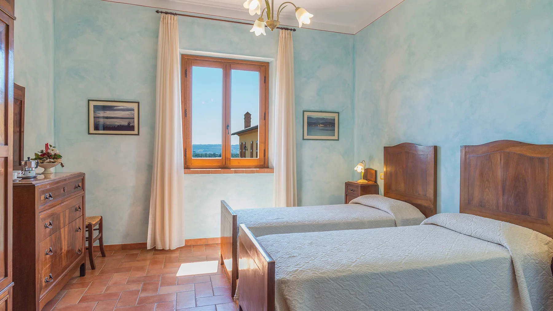 A bedroom with two beds and a window overlooking the sea.
