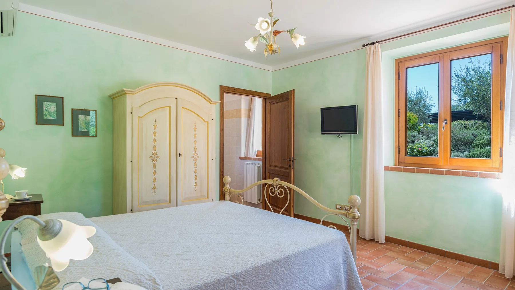 A bedroom with a bed, ornate wardrobe, and large window.