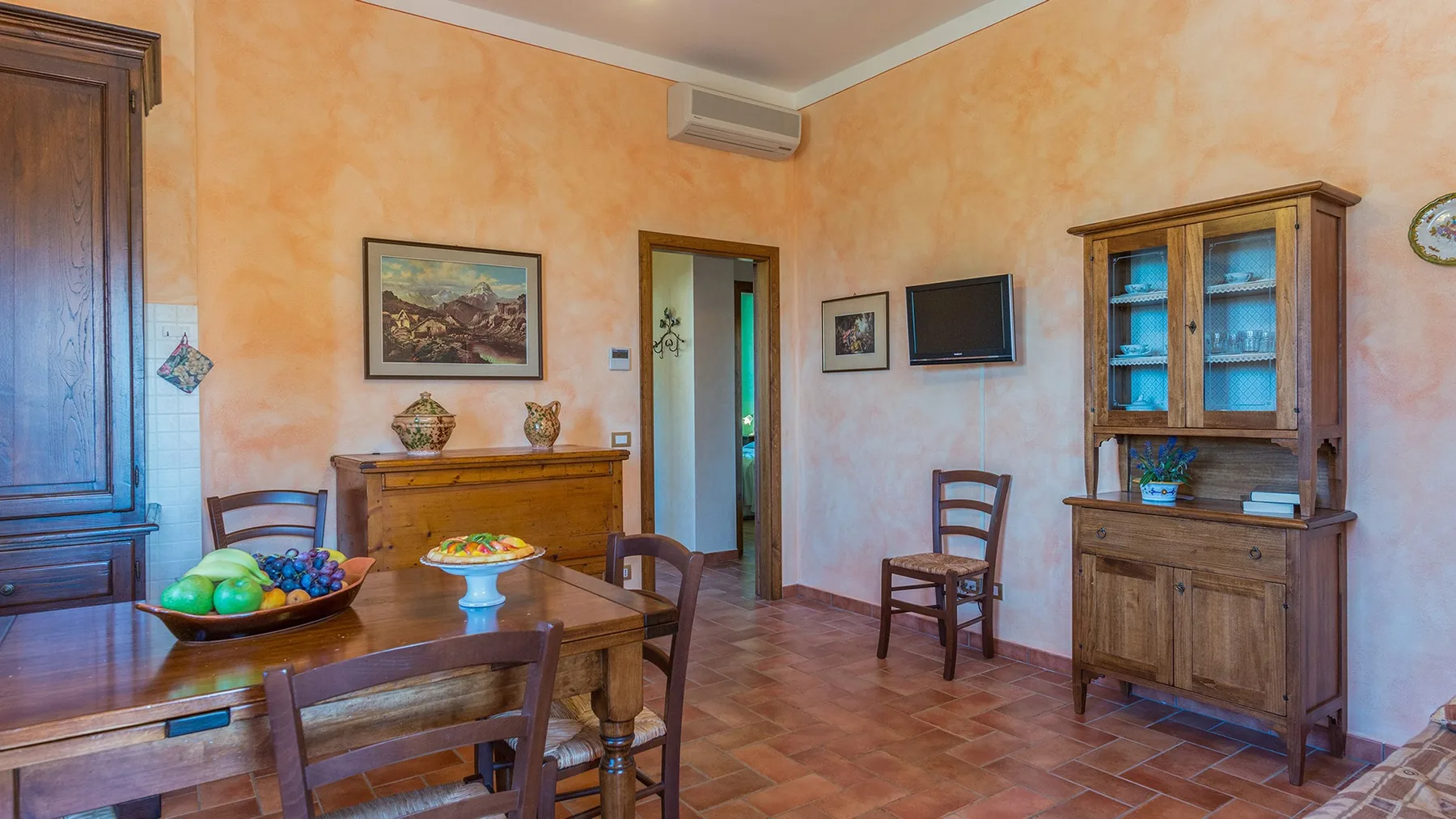 A dining area with a wooden table and chairs beside a glass-front cabinet.