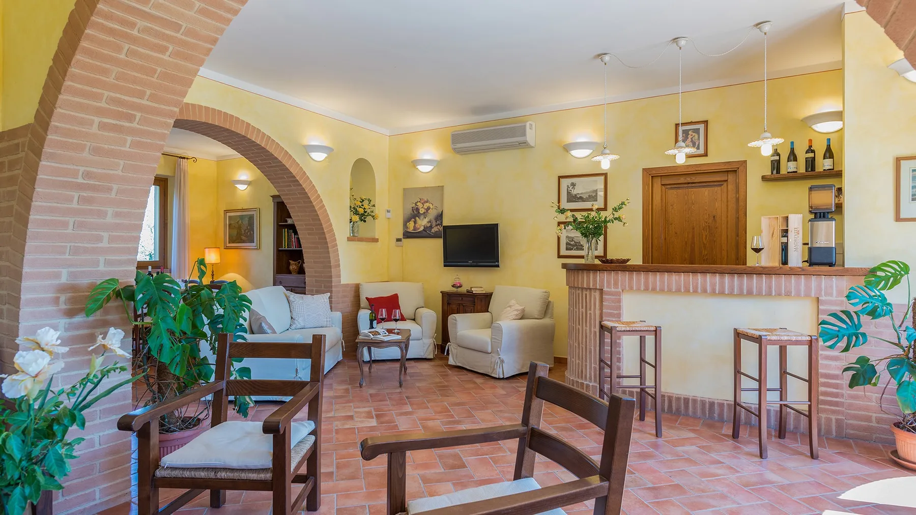 A living room with a brick arch, seating, and a television beside a bar.