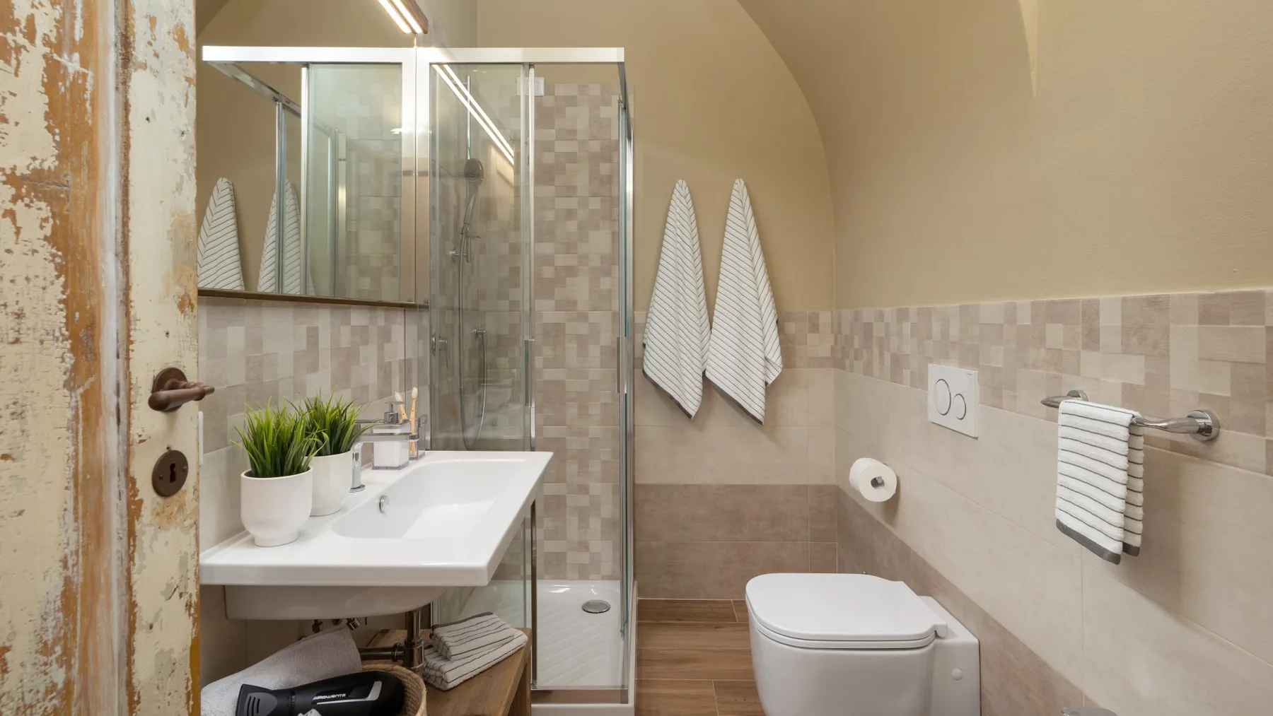 Un baño con ducha de vidrio, lavabo e inodoro.