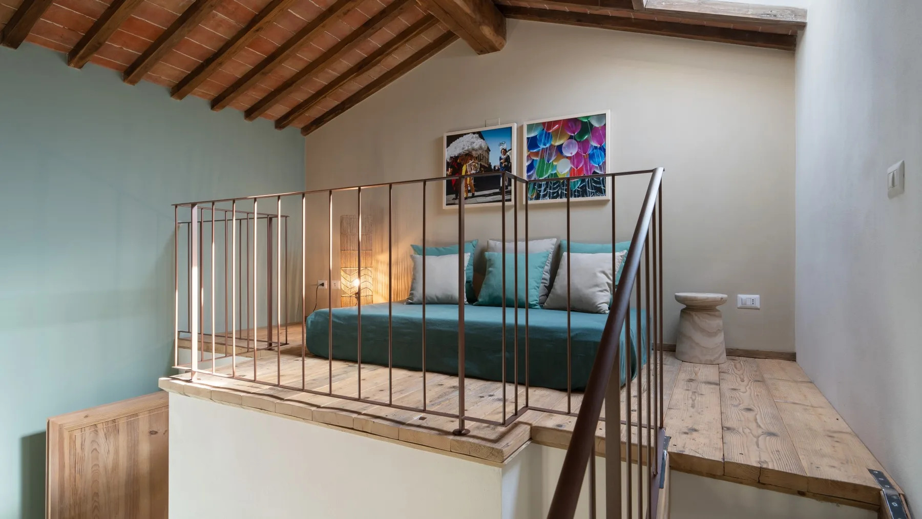 Una zona elevada para dormir tiene una cama bajo un techo inclinado de madera.