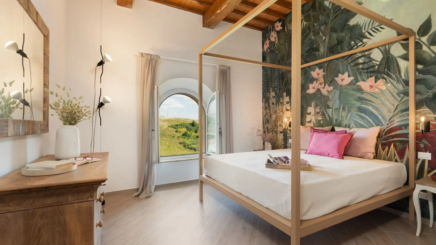 Un dormitorio con una cama con dosel junto a un mural de hojas y flores.