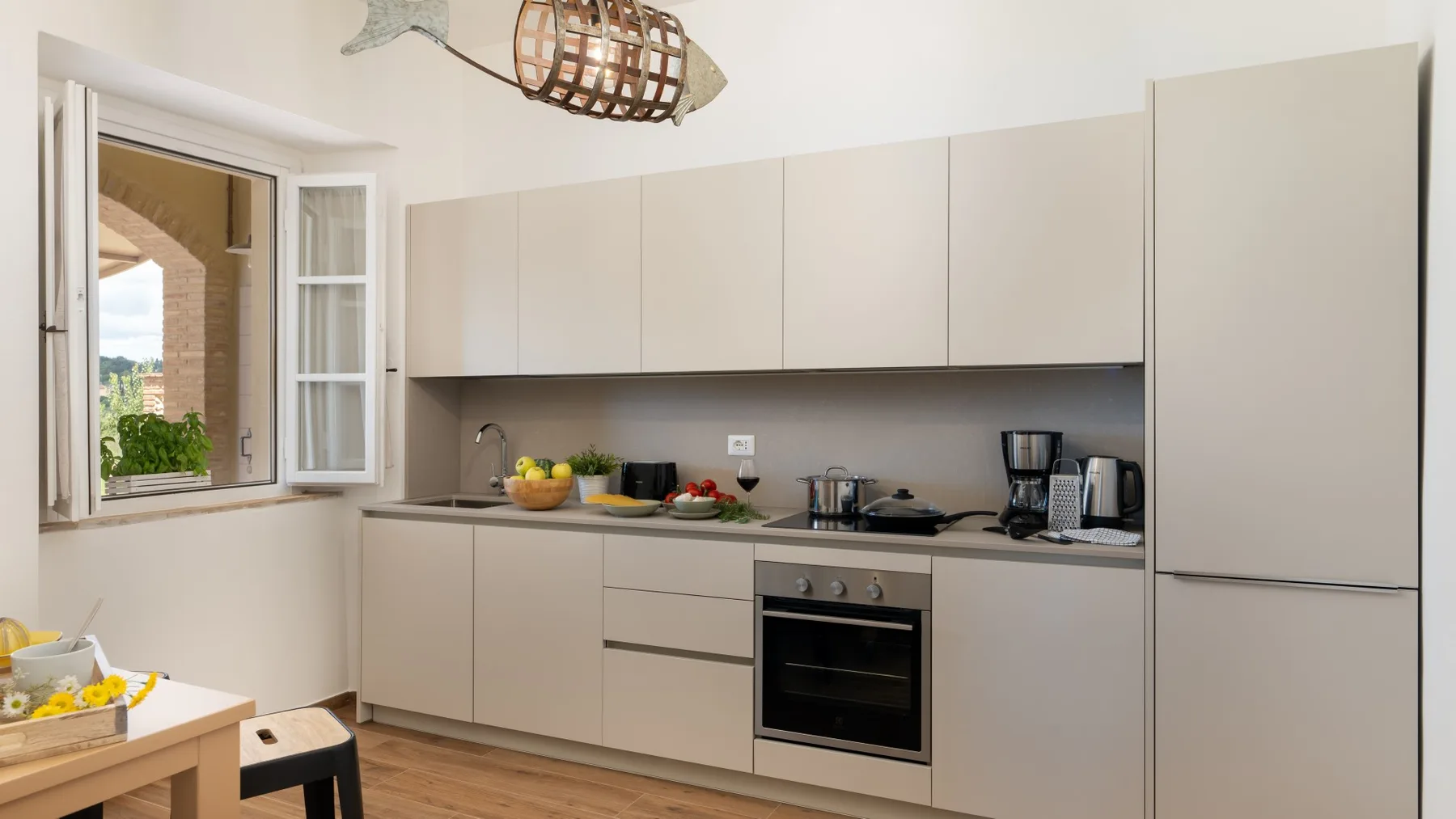Una cocina luminosa con gabinetes claros, una encimera y un horno integrado.