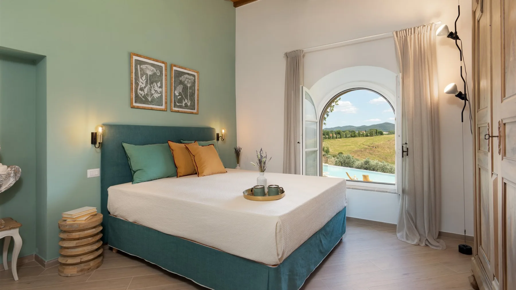 Un dormitorio con una cama y una ventana arqueada con vistas a un paisaje verde.