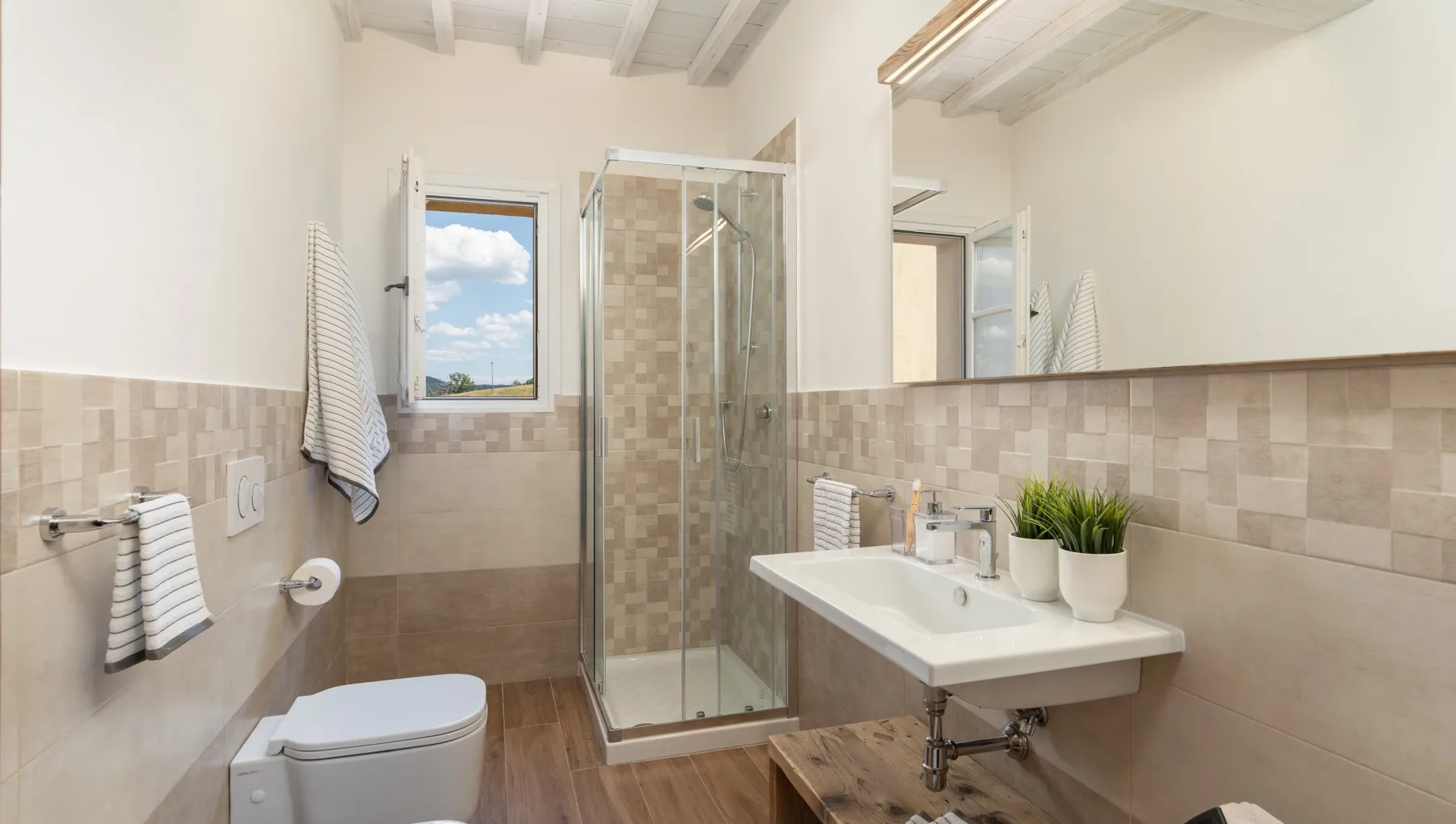 Un baño luminoso con ducha de cristal, lavabo y ventana.