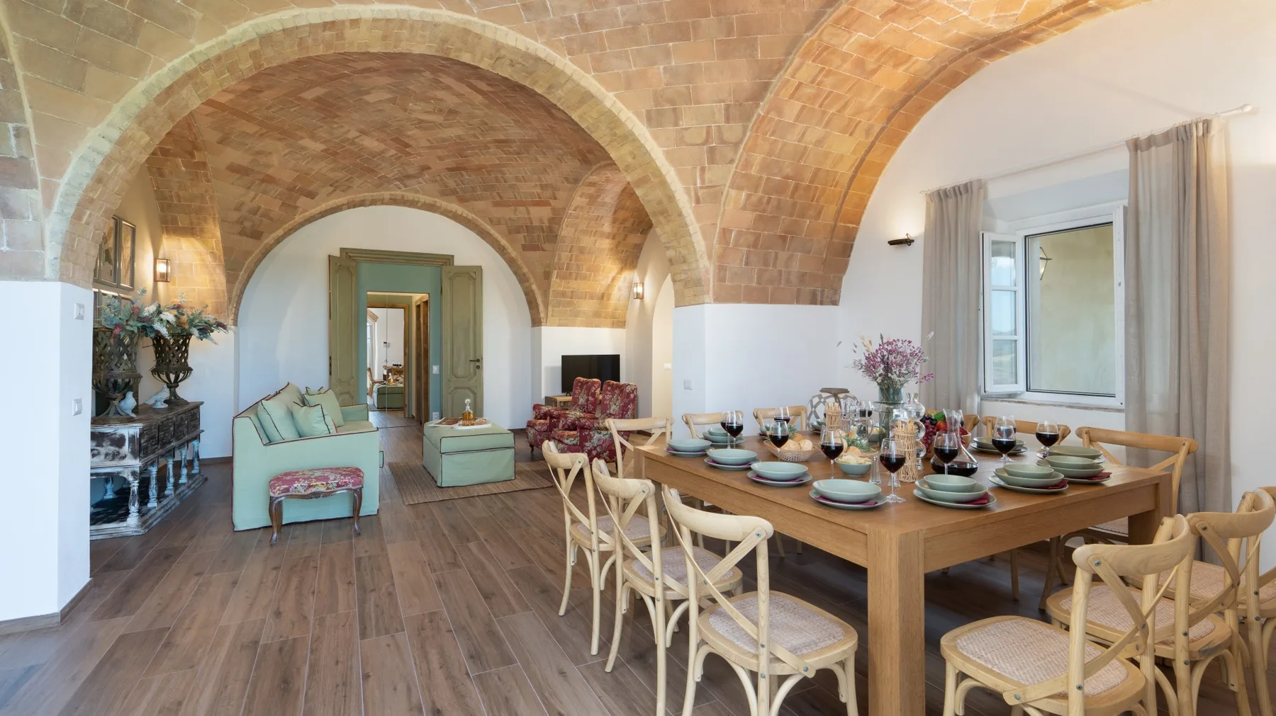 Un comedor con una mesa larga dispuesta bajo arcos de ladrillo.
