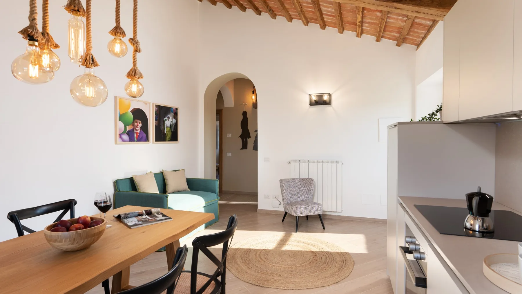 Una luminosa sala de estar y comedor con un sofá verde azulado y una mesa de madera.