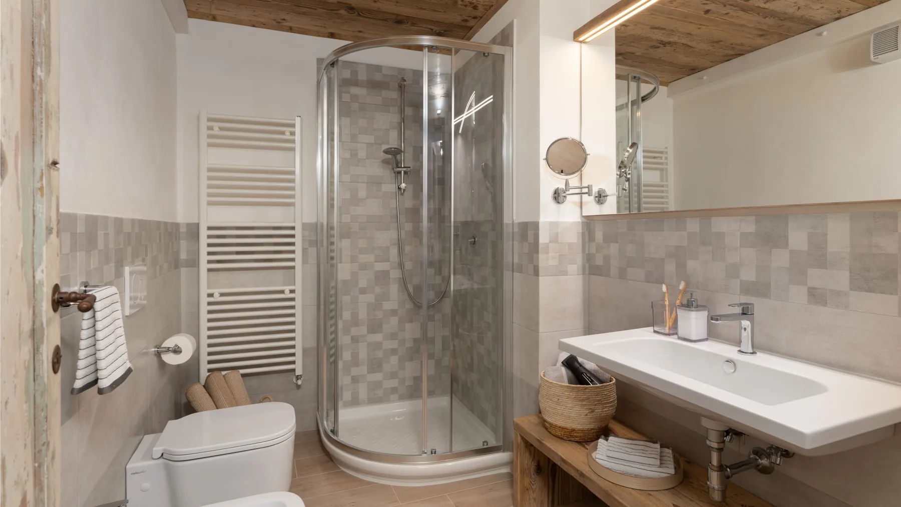 Un baño con ducha de cristal, inodoro y lavabo bajo un espejo grande.