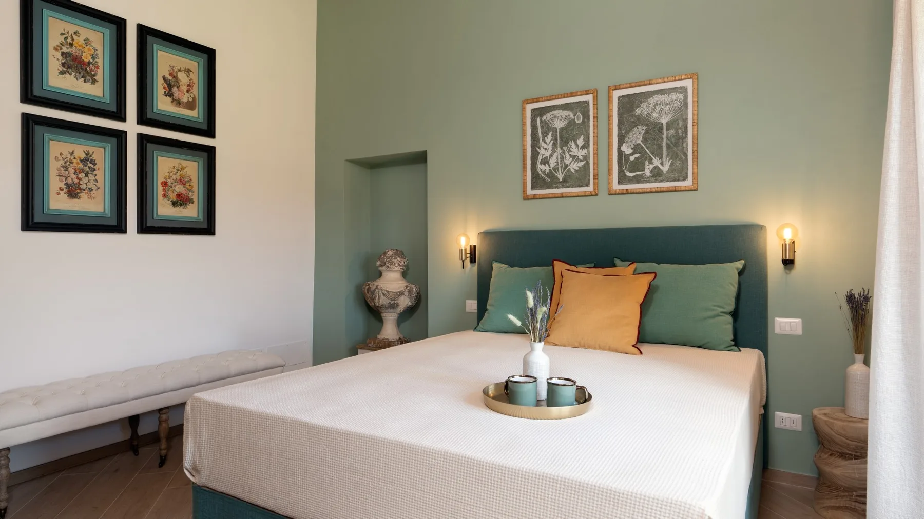Un dormitorio con una cama bien arreglada, cuadros enmarcados y un banco junto a la pared.