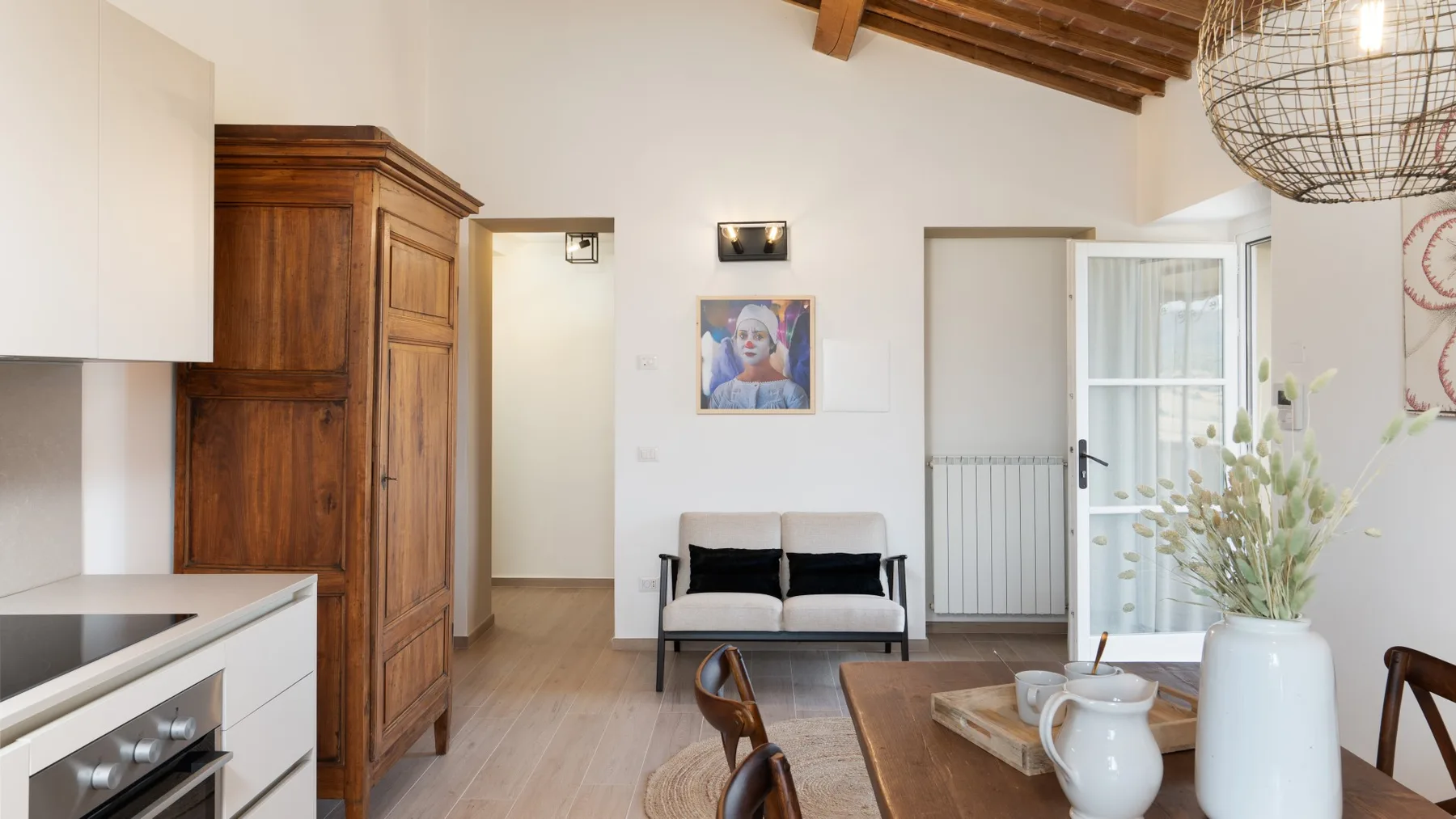Una luminosa sala de estar y comedor con una pequeña zona de asientos y vigas de madera en el techo.