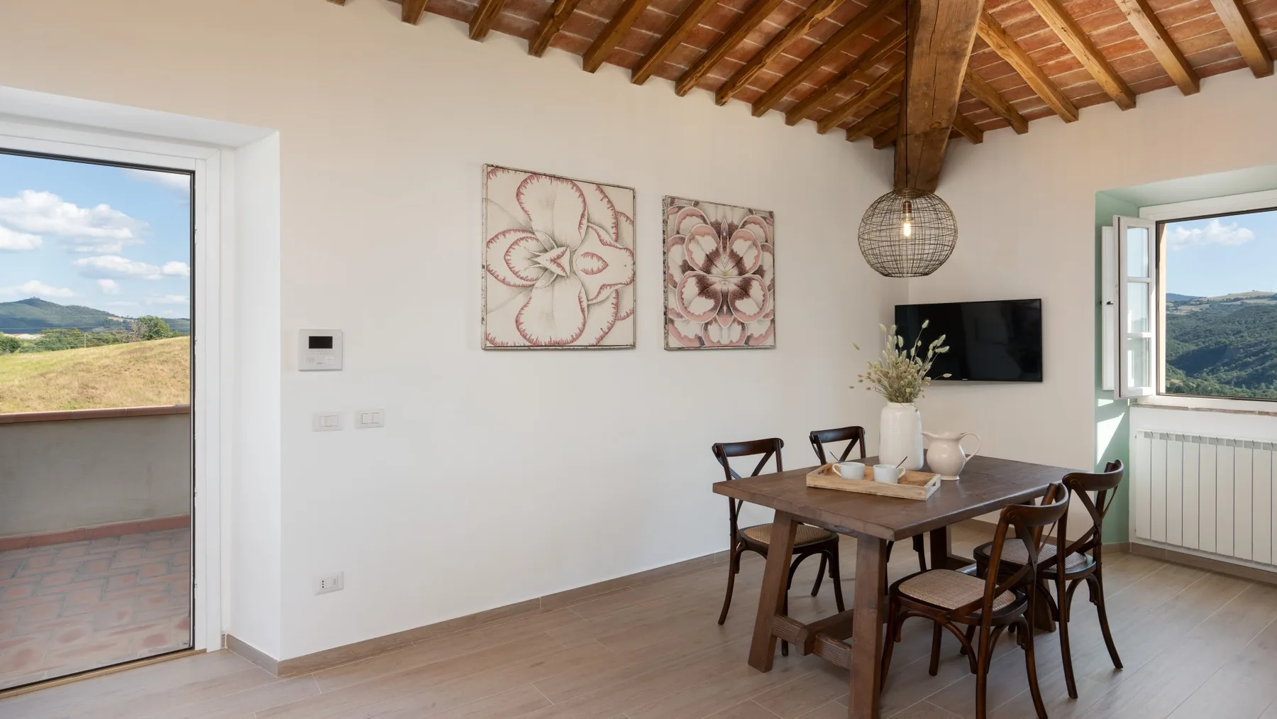 Un comedor con una mesa de madera bajo un techo con vigas.