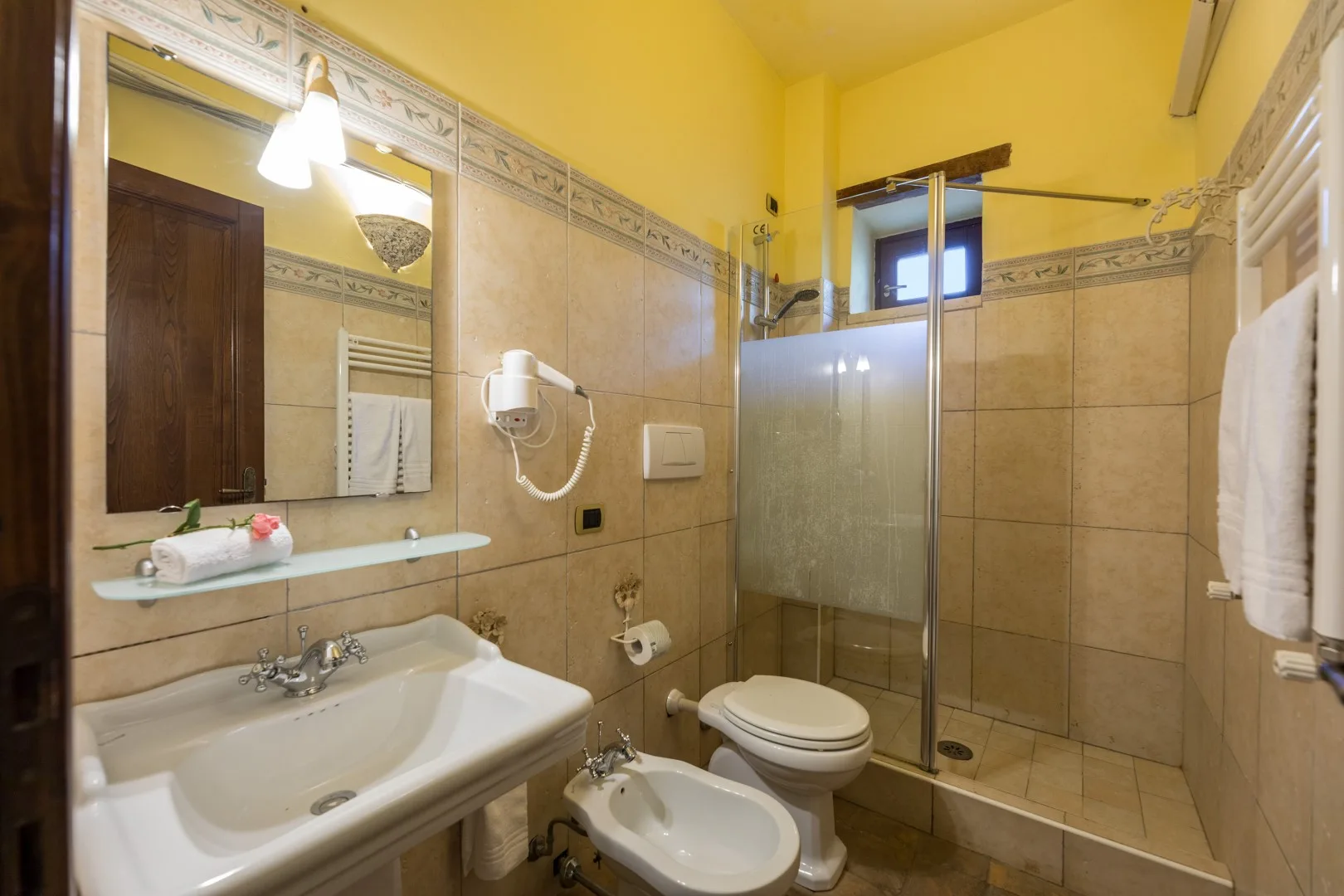 Un baño alicatado con lavabo, inodoro y ducha de vidrio.