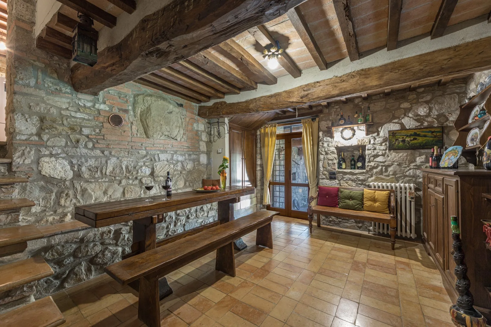 Un comedor rústico de piedra con una mesa larga de madera y un banco.