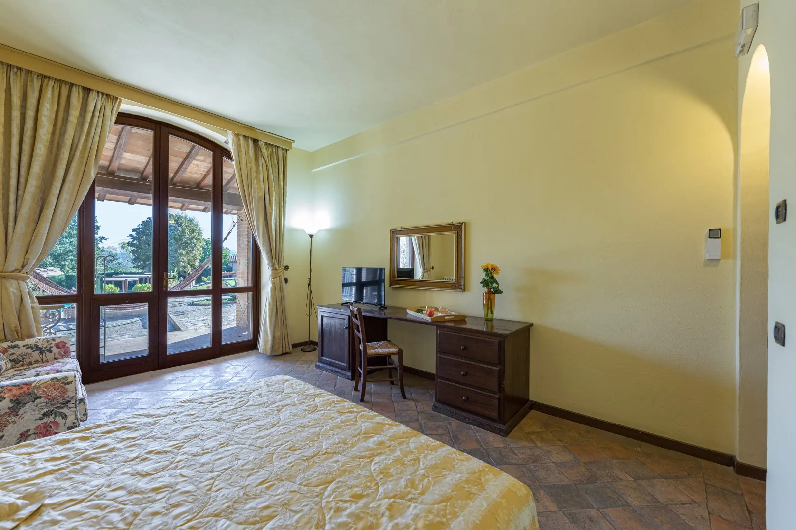 Un dormitorio con una cama, un escritorio y puertas de vidrio que dan a un balcón.