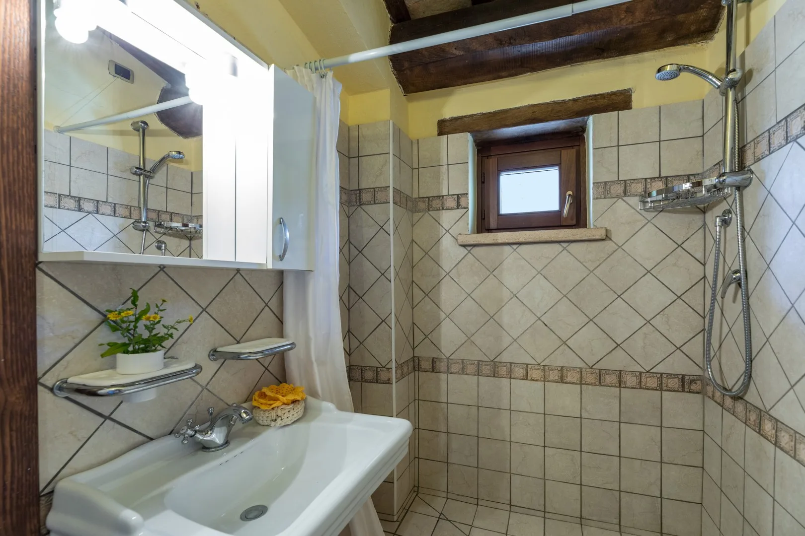 Un baño con azulejos, lavabo, ducha y una ventana pequeña.