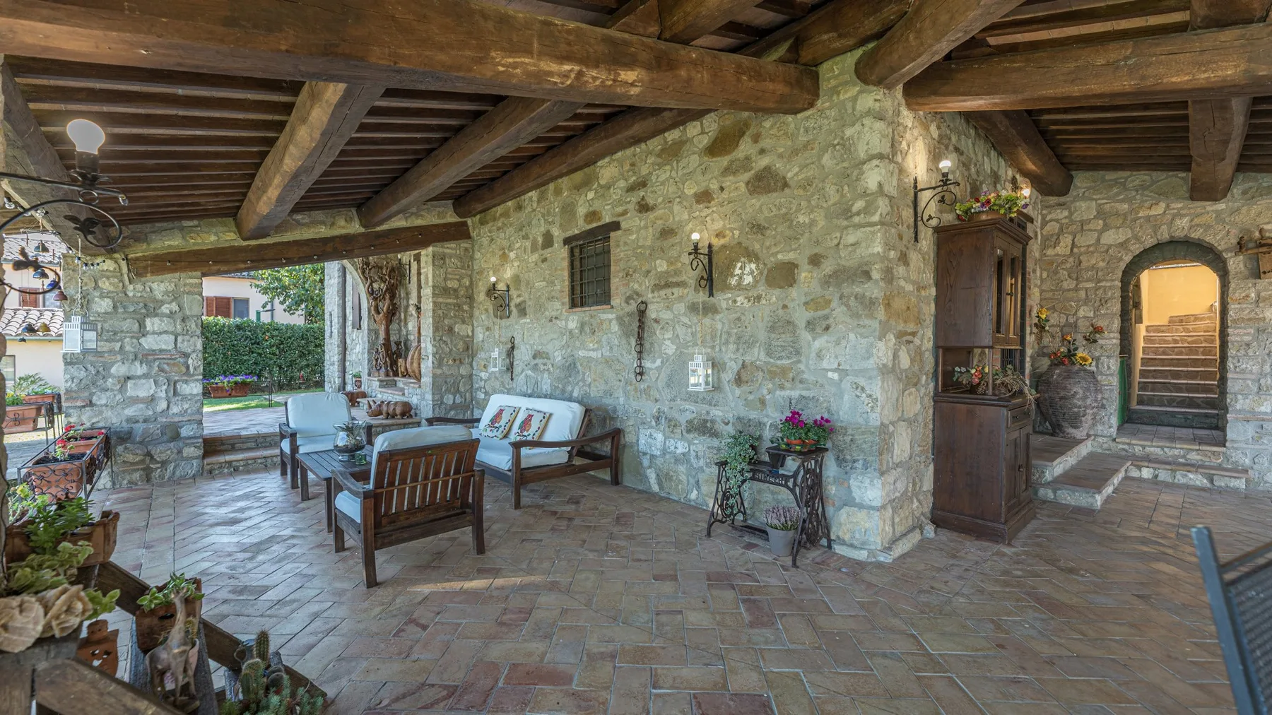 Un patio cubierto con paredes de piedra, asientos de madera y vigas expuestas.
