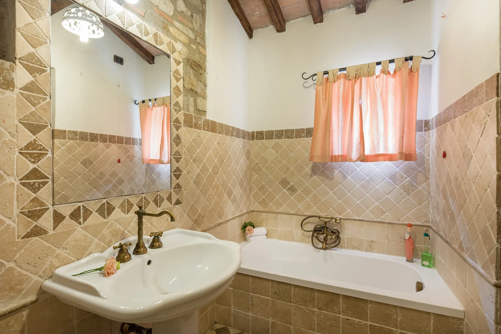 Un baño con azulejos, bañera, lavabo y cortinas naranjas.