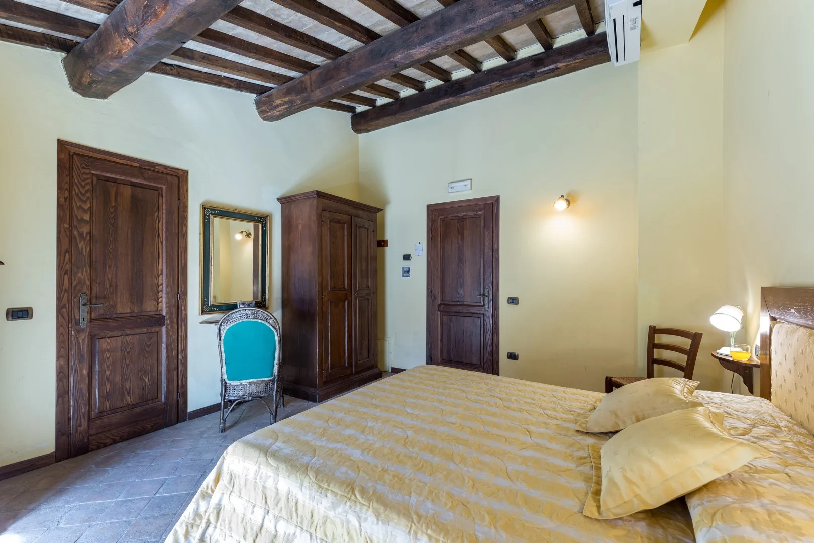 Un dormitorio con una cama grande, muebles de madera oscura y vigas de techo a la vista.
