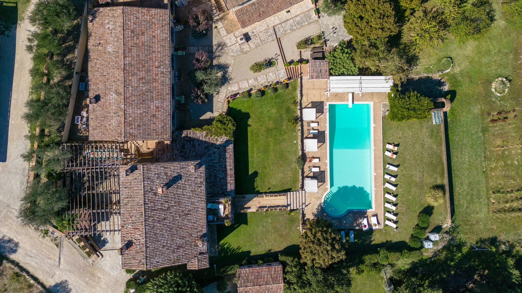 Una vista aérea muestra una piscina junto a un césped y edificios circundantes.