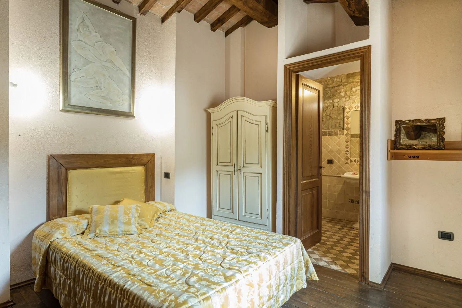 Un dormitorio con una cama, un armario y una puerta abierta a un baño alicatado.