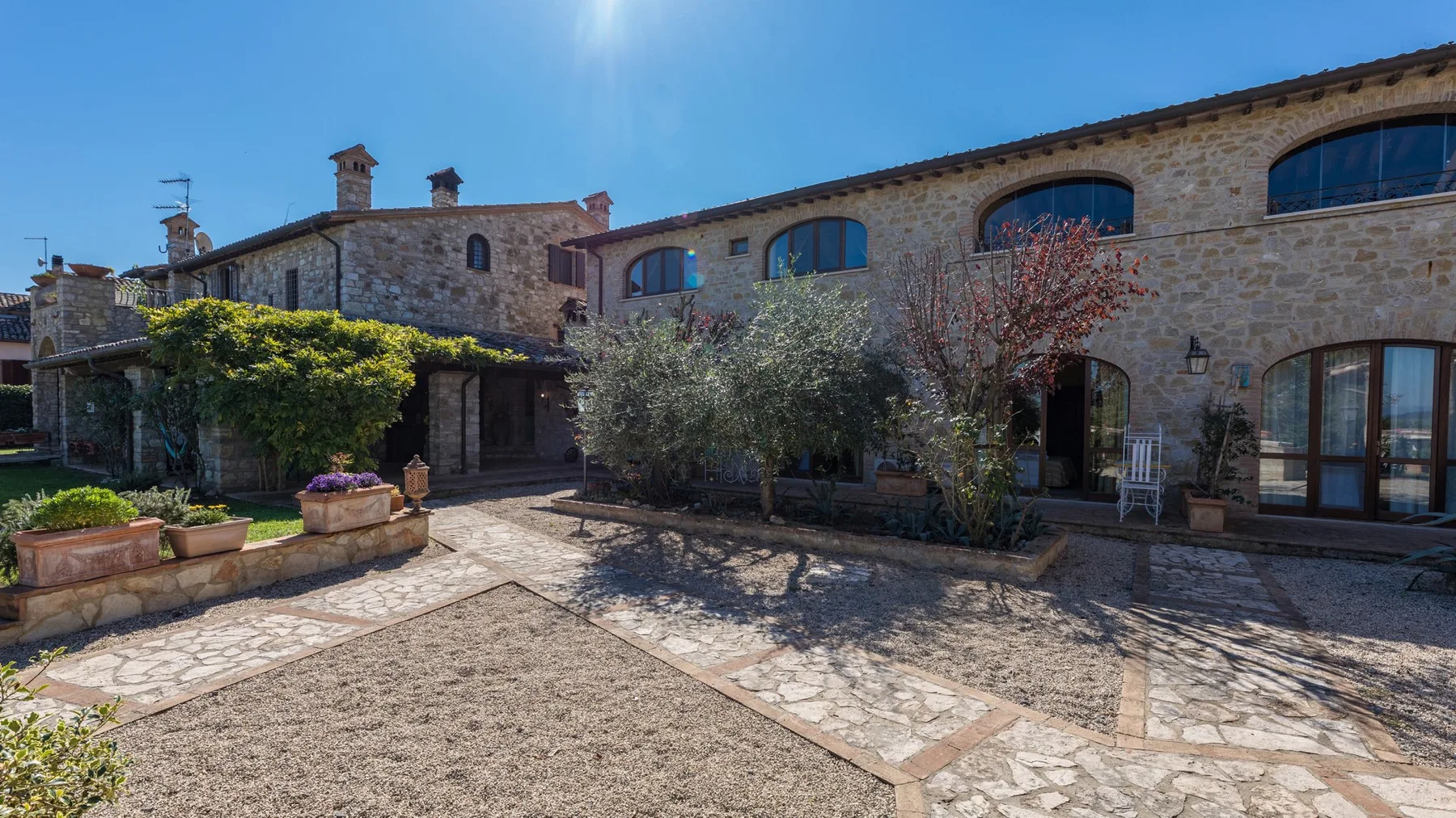 Un edificio de piedra da a un patio pavimentado con árboles y jardineras.