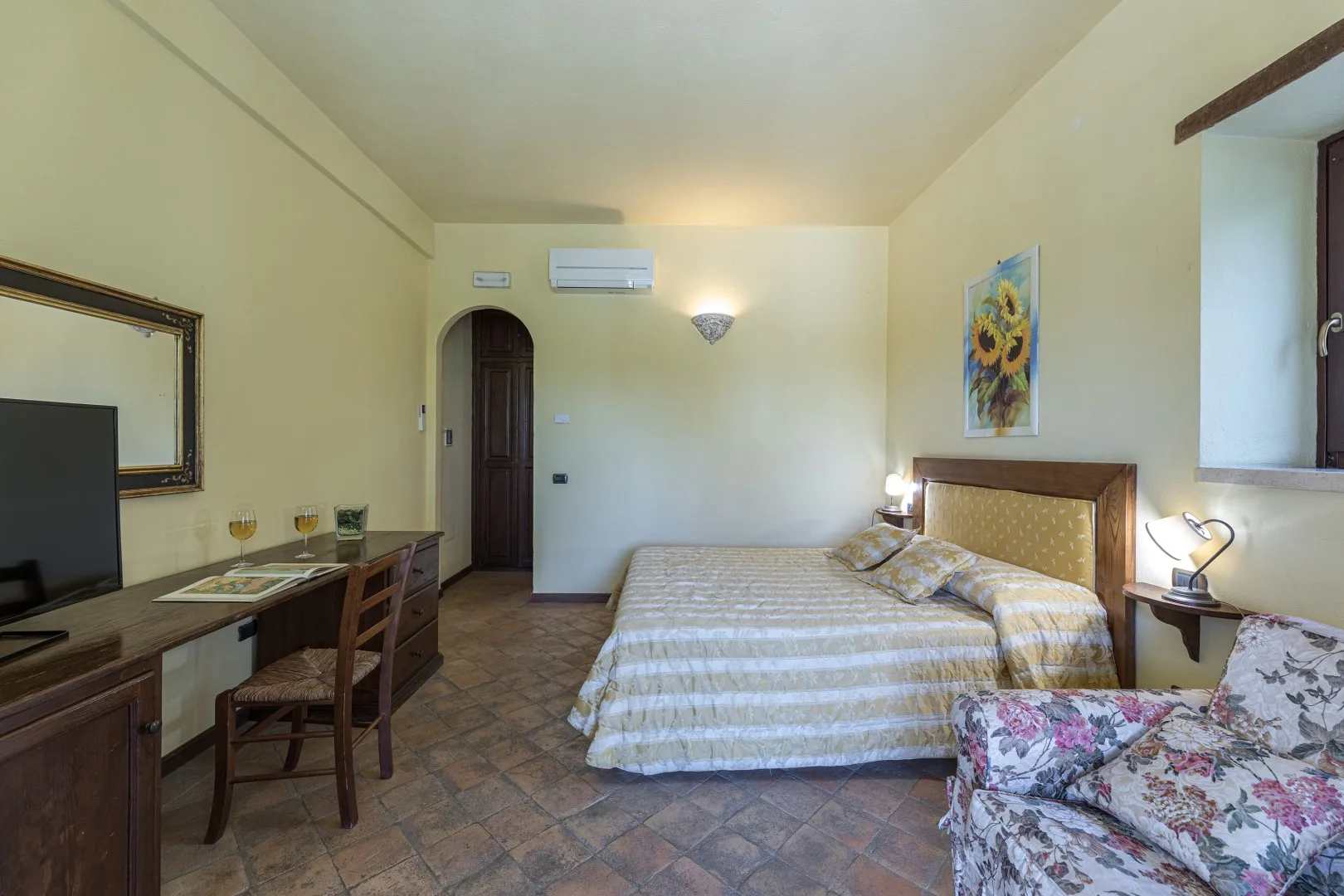 Un dormitorio con cama doble, escritorio y asiento floral.