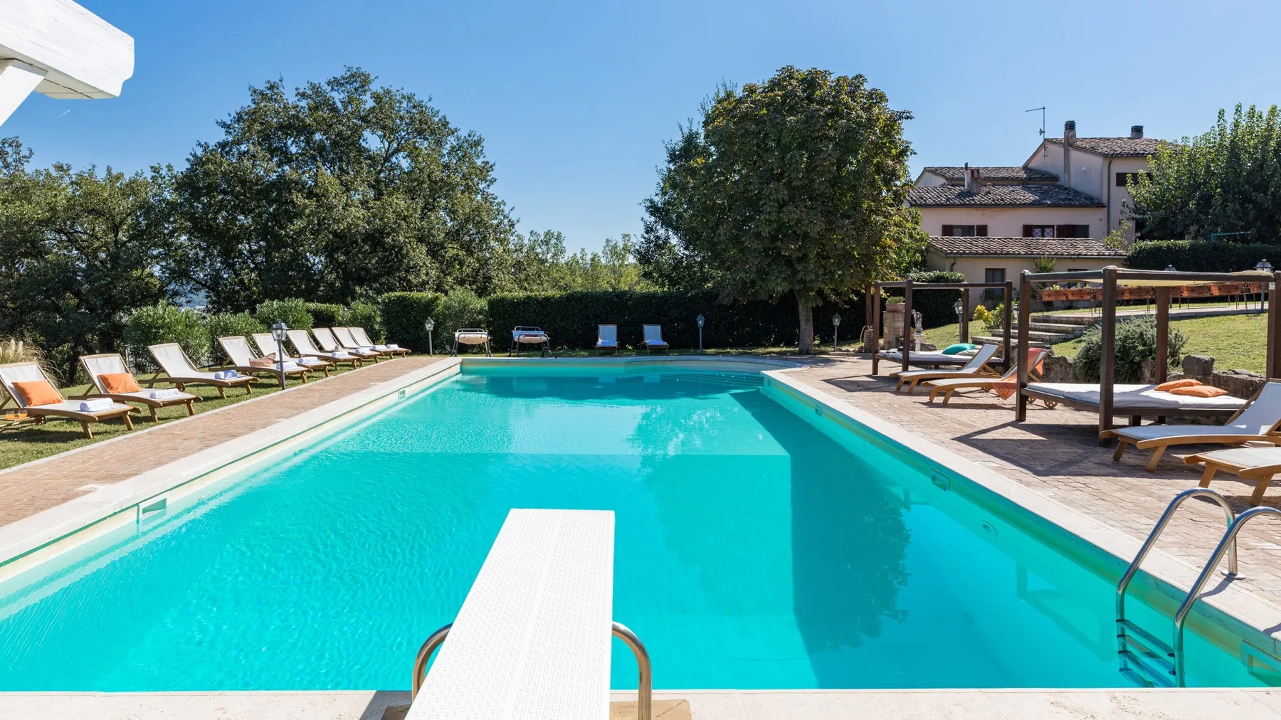 Una piscina al aire libre con asientos de descanso y árboles alrededor de la terraza.