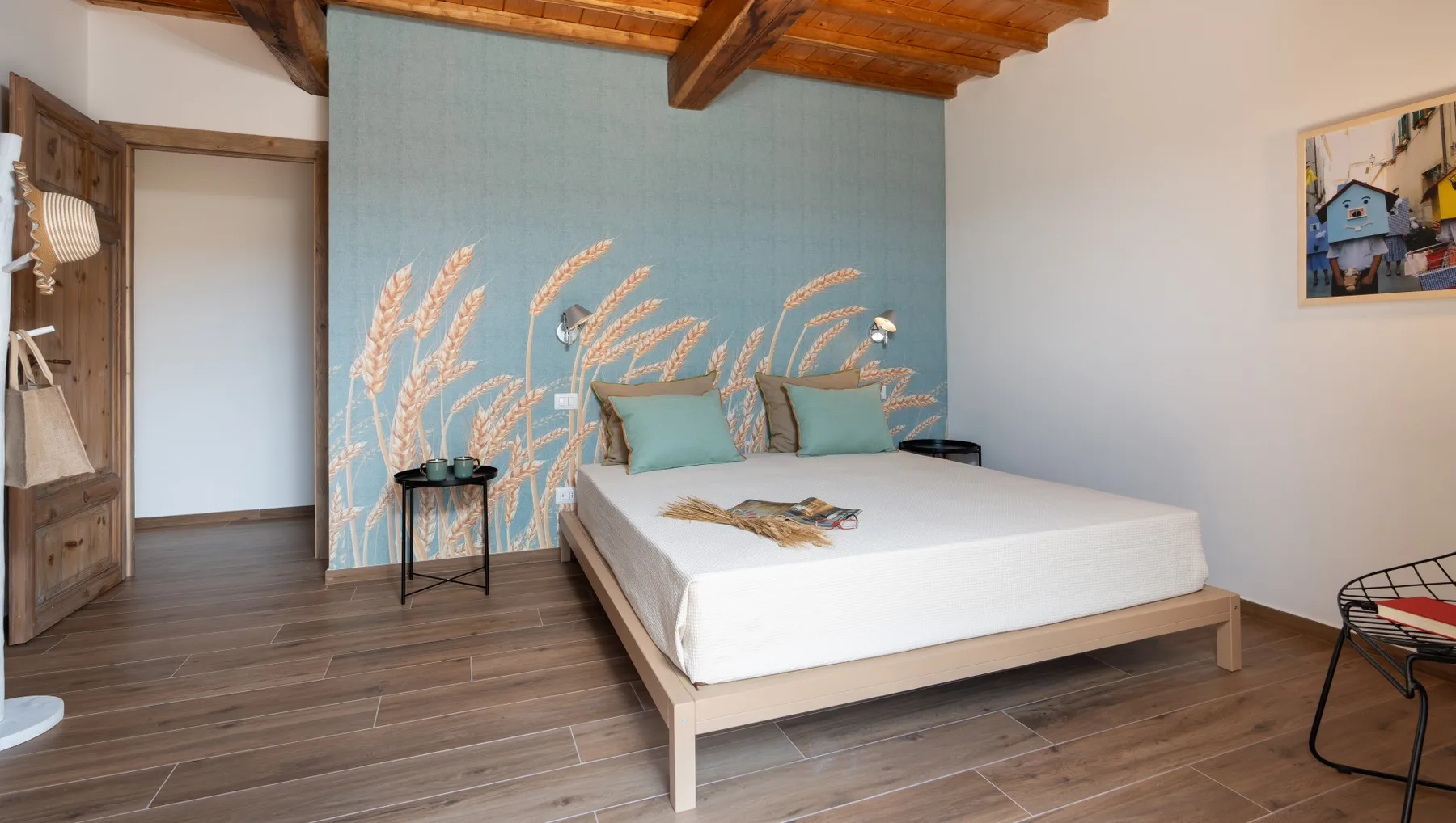 A bedroom with a white bed against a blue mural wall.