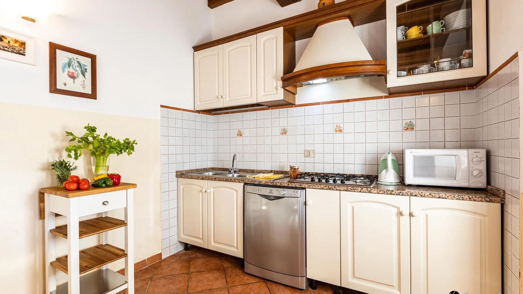 Una cocina luminosa con armarios blancos, paredes de azulejos y una encimera.