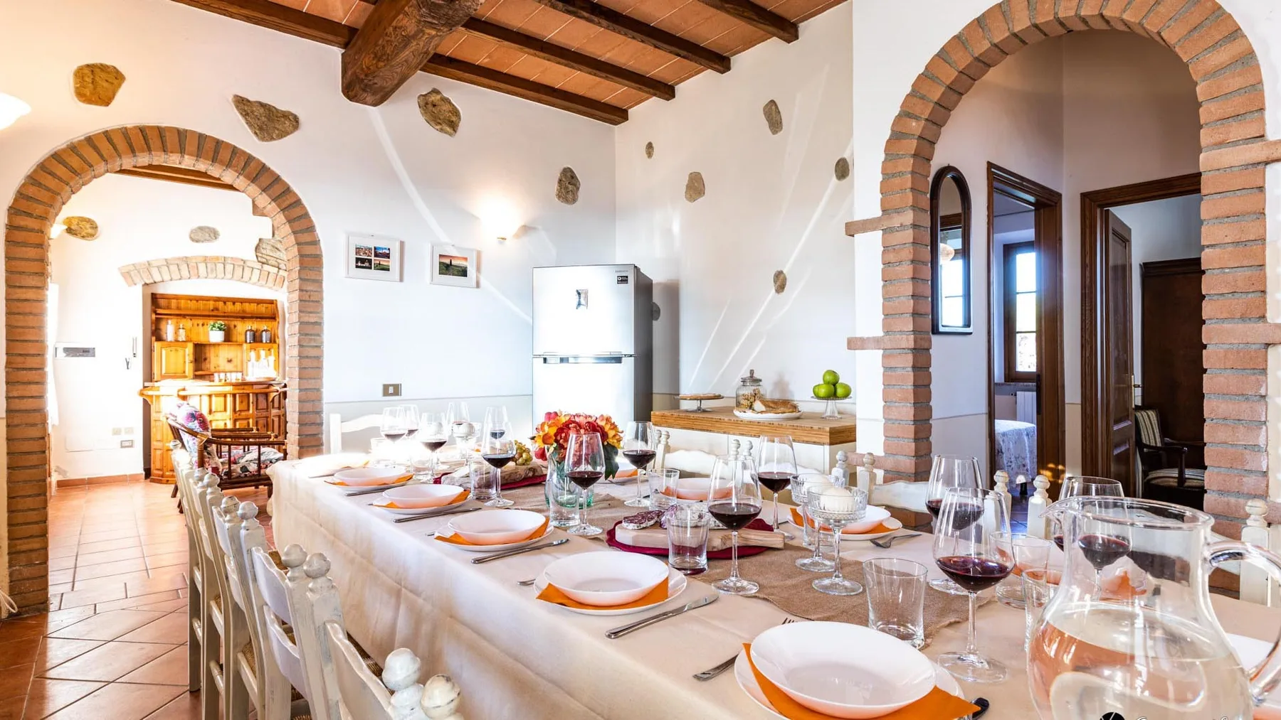 Un comedor con una mesa larga preparada con platos y cristalería.